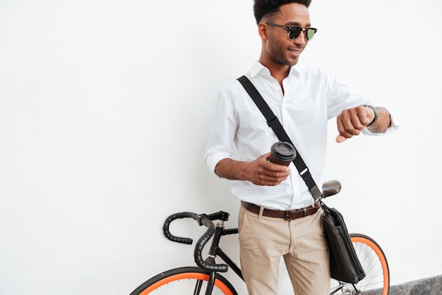 Hombre africano con bicicleta tomando café.