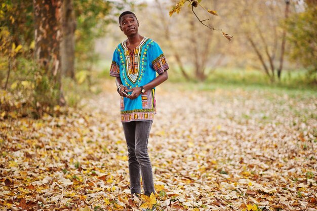 Hombre africano en camisa tradicional de África en el parque de otoño