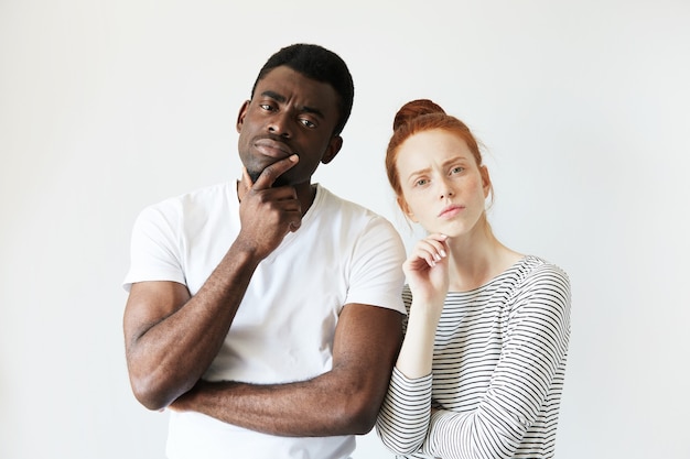 Hombre africano en camiseta blanca y mujer caucásica pelirroja en top rayado