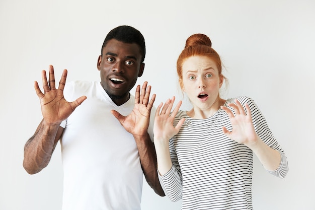 Hombre africano en camiseta blanca y mujer caucásica pelirroja en top rayado