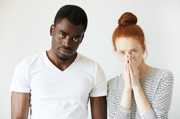 Hombre africano en camiseta blanca y mujer caucásica pelirroja en top rayado