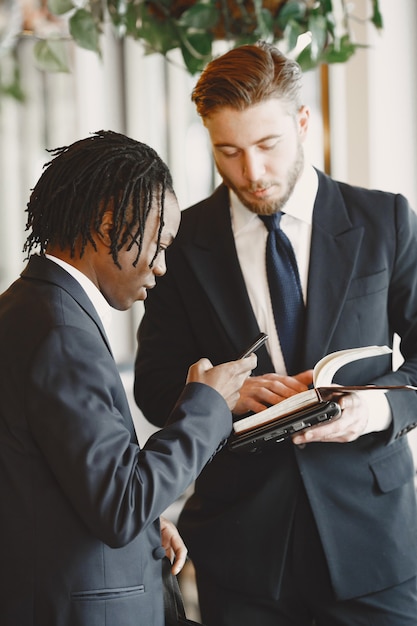 Hombre africano. Chico de traje negro. Las personas mixtas trabajan juntas.