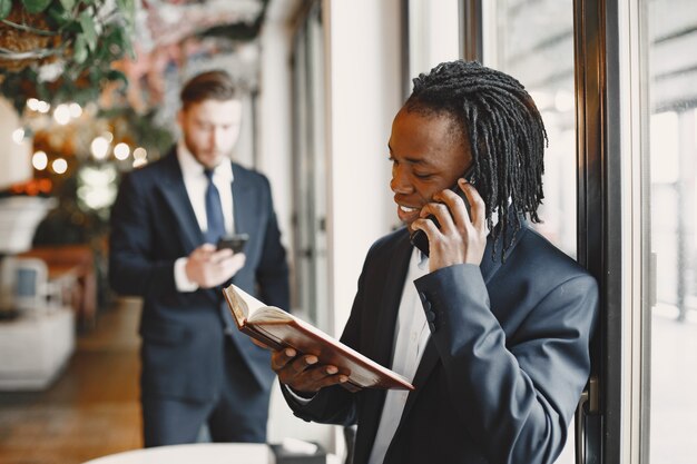 Hombre africano. Chico de traje negro. Las personas mixtas trabajan juntas.