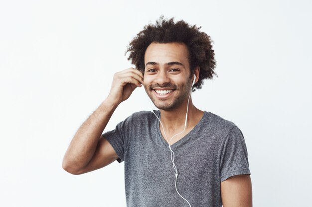 Hombre africano feliz apagar auriculares sonriendo.