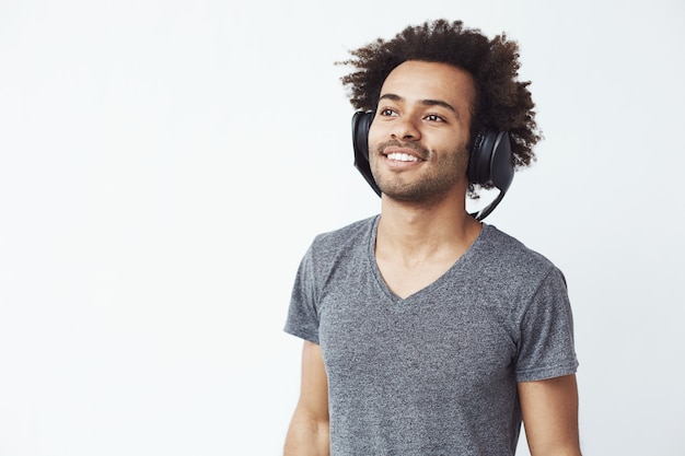 Foto gratuita hombre africano feliz sonriendo escuchando música en auriculares.