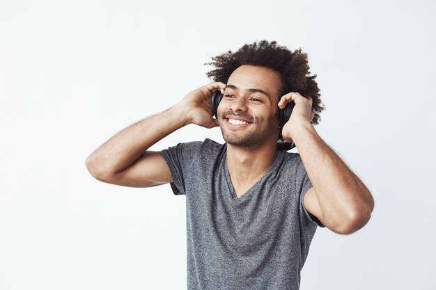 Hombre africano feliz sonriendo escuchando música en auriculares.