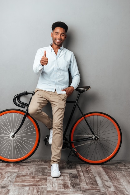 Hombre africano joven feliz que muestra los pulgares para arriba.