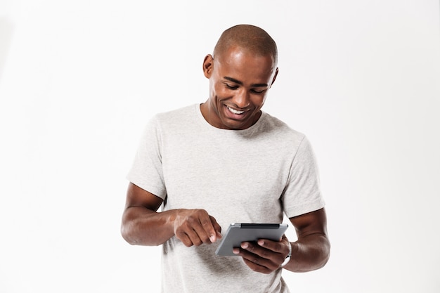 Hombre africano joven feliz que usa la tableta.