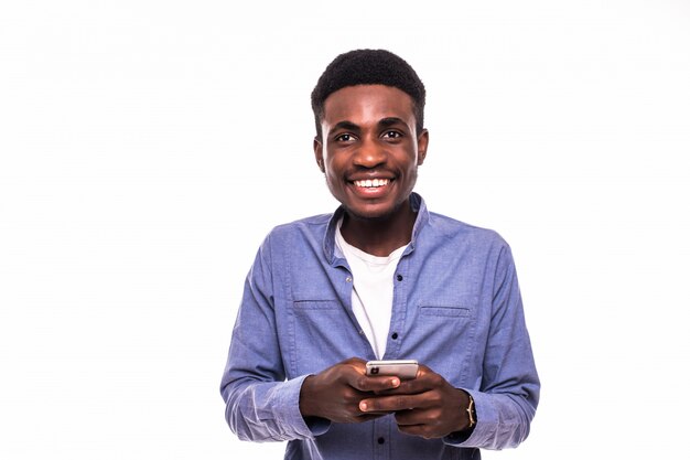 Hombre africano joven que usa el teléfono móvil aislado contra la pared blanca