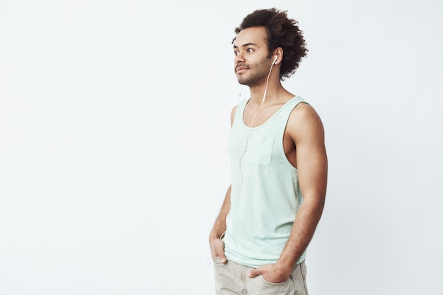 Hombre africano joven sonriendo escuchando música en auriculares.