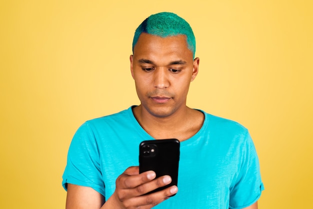 Hombre africano negro en casual en la pared amarilla con mirada seria de teléfono móvil en la pantalla leer noticias
