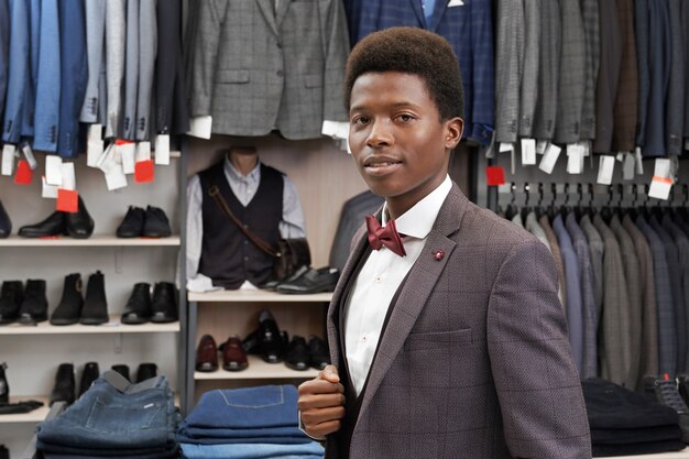 Hombre africano posando en boutique de camisa blanca, elegante traje.