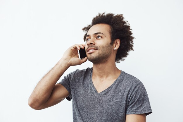 Foto gratuita hombre africano positivo sonriendo hablando por teléfono.