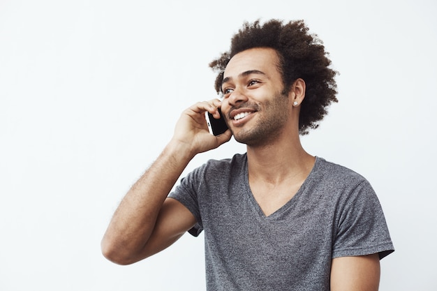 Hombre africano positivo sonriendo hablando por teléfono.