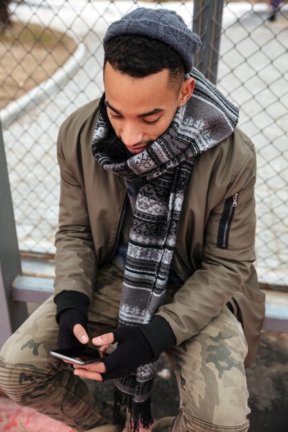 Hombre africano serio que usa el teléfono celular al aire libre