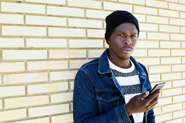 Hombre afro americano con smartphone enfrente de muro