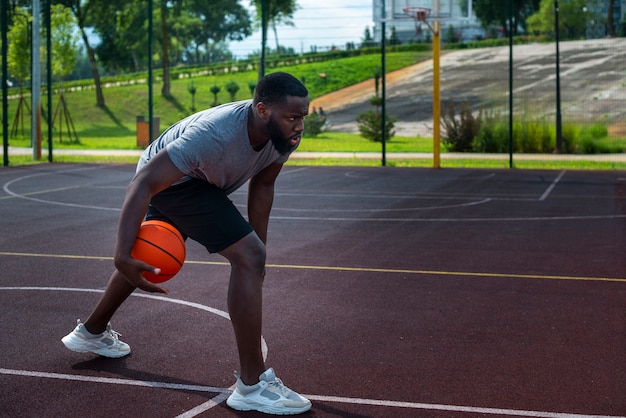 Hombre afro jugando baloncesto en el campo