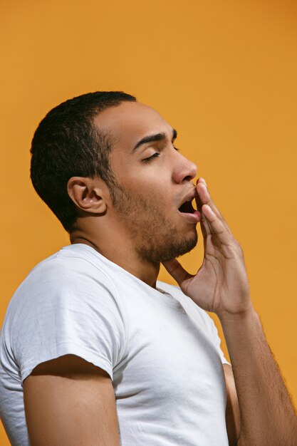 Hombre afroamericano aburrido quiere dormir contra el espacio naranja