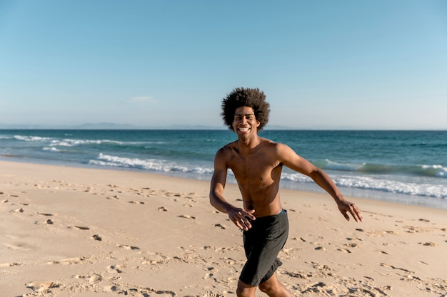 Hombre afroamericano alegre corriendo a orilla del mar