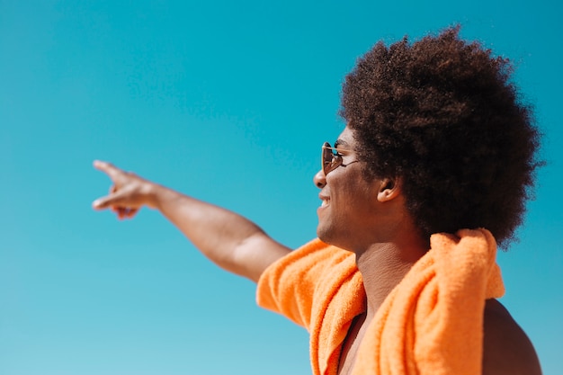 Foto gratuita hombre afroamericano apuntando lejos contra el cielo