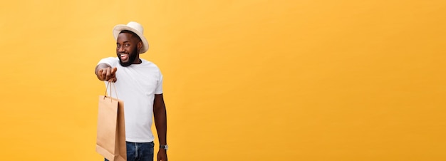 Hombre afroamericano con bolsas de papel de colores aislados sobre fondo amarillo