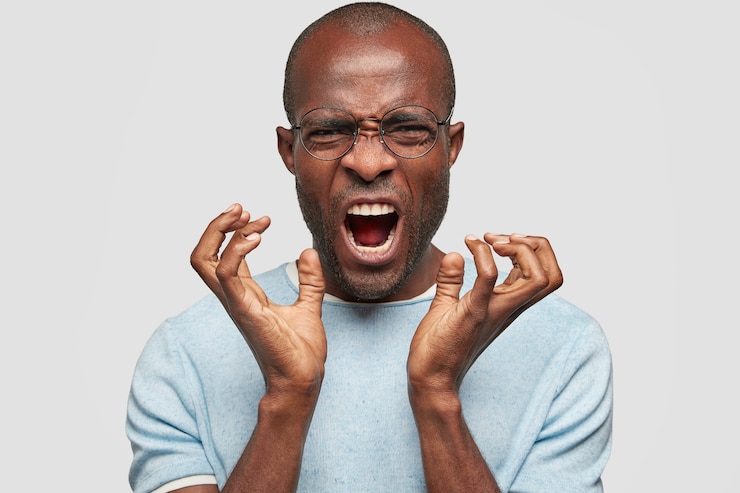 Foto gratuito un hombre afroamericano calvo de piel oscura hace gestos de agresión, exclama negativamente, se siente molesto por su falta, frunce el ceño con disgusto, se para contra la pared de cemento blanco. ¡no me molestes!