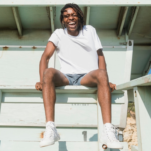 Hombre afroamericano en camiseta blanca en la playa.