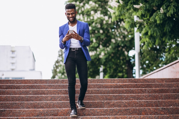 Hombre afroamericano en chaqueta azul usando teléfono