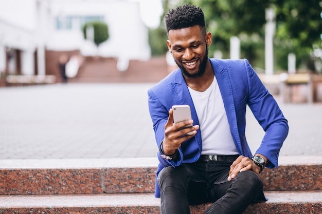 Hombre afroamericano en chaqueta azul usando teléfono