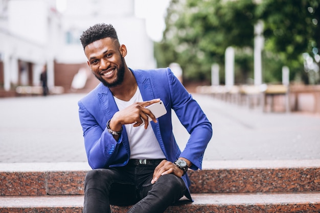 Hombre afroamericano en chaqueta azul usando teléfono