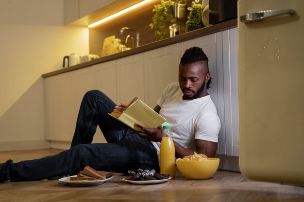 Hombre afroamericano comiendo y leyendo