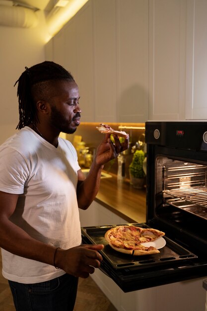 Hombre afroamericano comiendo pizza a altas horas de la noche