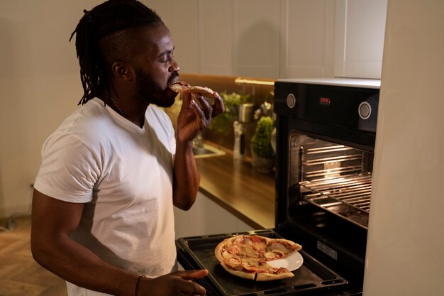 Hombre afroamericano comiendo pizza a altas horas de la noche