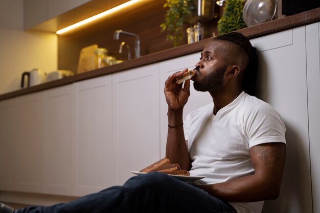 Hombre afroamericano comiendo en el suelo