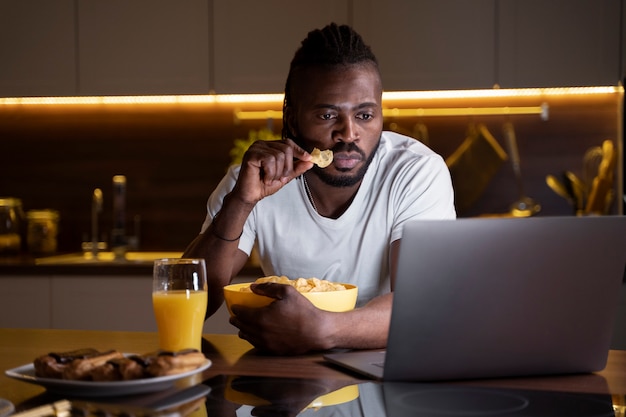 Hombre afroamericano comiendo tarde en la noche