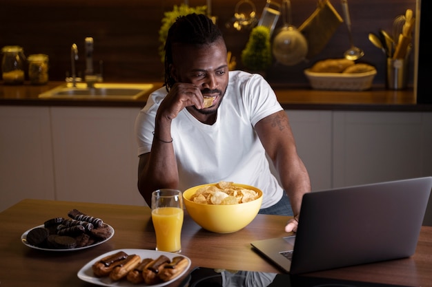 Hombre afroamericano comiendo tarde en la noche