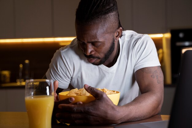 Hombre afroamericano comiendo tarde en la noche