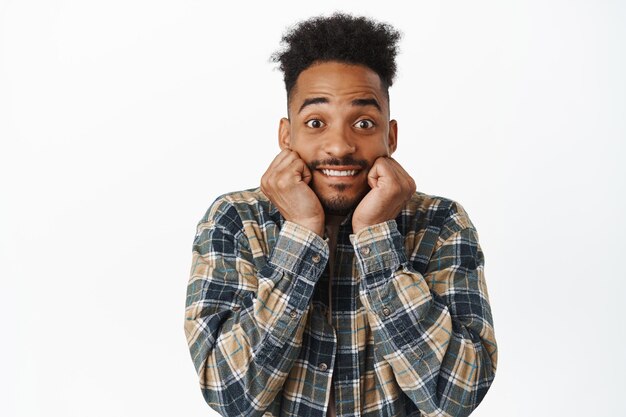 Hombre afroamericano emocionado sonriendo, mirando con admiración y emoción, esperando algo emocionante, anticipando un gran anuncio de noticias, viendo o contemplando un evento interesante.