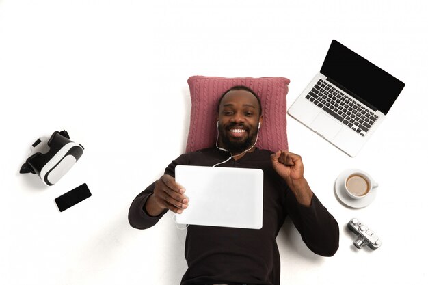 Hombre afroamericano emocional usando gadgets, tecnologías. Dispositivos que conectan personas durante la cuarentena