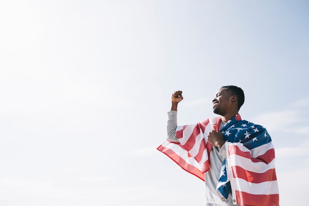 Foto gratuita hombre afroamericano envuelto en la bandera de estados unidos.