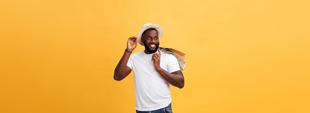 Hombre afroamericano feliz sosteniendo bolsas de compras en el concepto de vacaciones de fondo amarillo