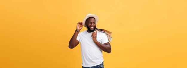 Hombre afroamericano feliz sosteniendo bolsas de compras en el concepto de vacaciones de fondo amarillo