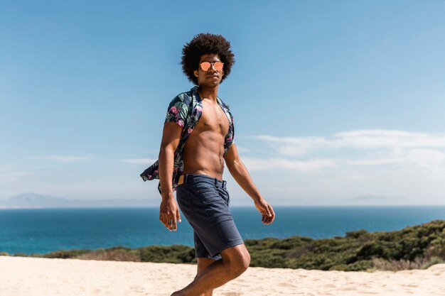 Hombre afroamericano guapo caminando en la playa