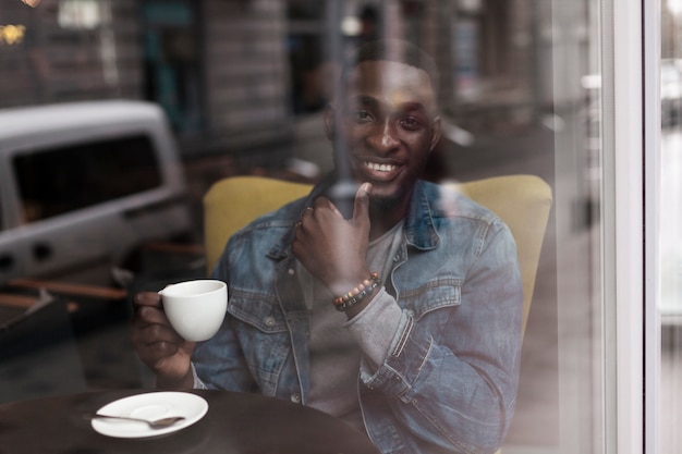 Foto gratuita hombre afroamericano guapo posando a través de la ventana