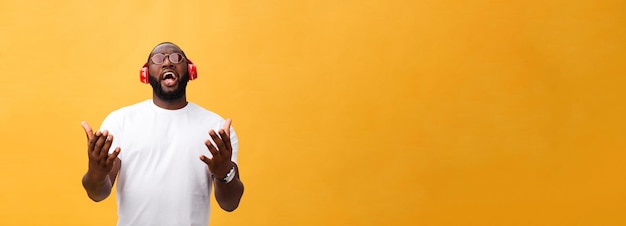 Hombre afroamericano joven con auriculares y disfrutar de la música sobre fondo de oro amarillo