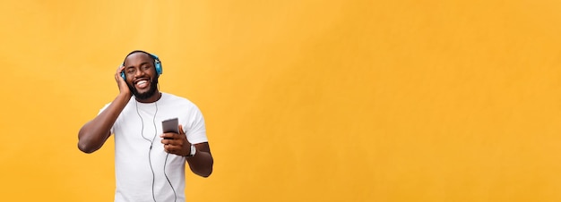 Hombre afroamericano joven con auriculares y disfrutar de la música sobre fondo de oro amarillo