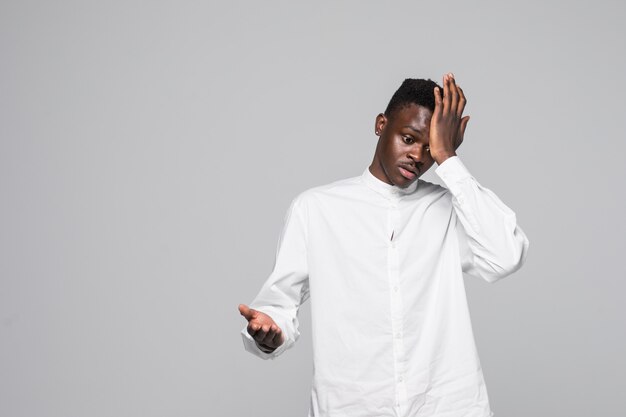 El hombre afroamericano joven que lleva la camiseta blanca sorprendió con la mano en la cabeza por error, recuerda error. Olvidé, concepto de mala memoria.