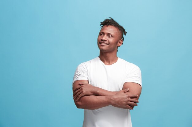 El hombre afroamericano de negocios feliz de pie y sonriendo contra el azul.