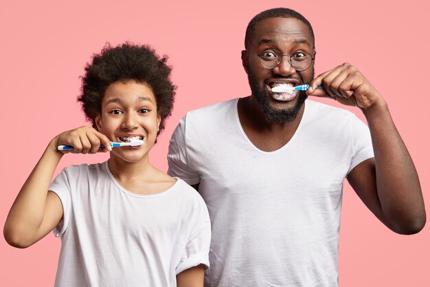 Hombre afroamericano y niño cepillarse los dientes