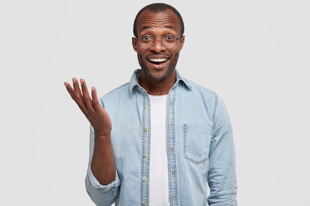 El hombre afroamericano de piel oscura positiva se ríe mientras escucha algo gracioso